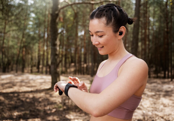 Mulher praticando atividade física ao ar livre e interagindo com um smartwatch